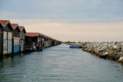 Canal amidst houses and buildings against sky