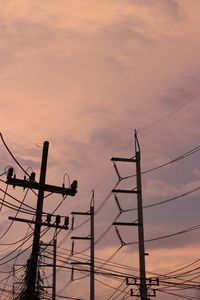 Low angle view of electricity pylon against sky during sunset