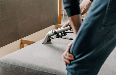 Close-up image of professional cleaning service doing a deep clean of sofa in living room.