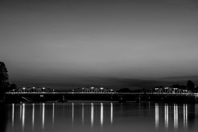 Illuminated bridge over river against sky at night