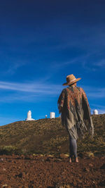 Rear view of man standing on field against sky