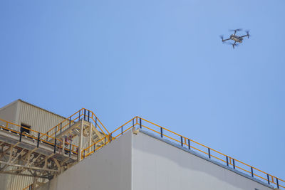 Low angle view of crane against clear blue sky
