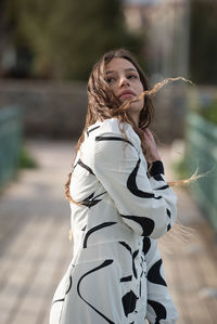 Young woman with long hair wearing black and white dress posing fashion outdoors.