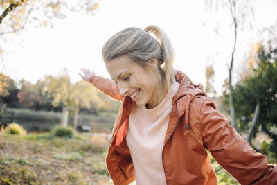 Portrait of happy young woman balancing in autumnal park