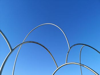 Low angle view of metal fence against clear blue sky