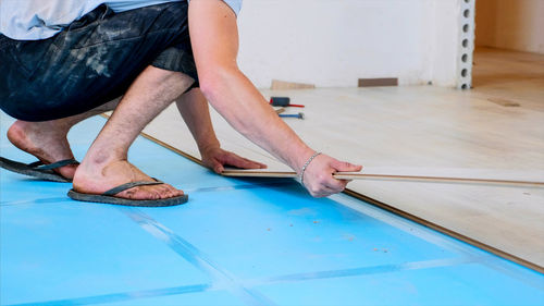 Low section of man measuring plank in workshop