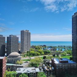 Modern buildings by sea against blue sky