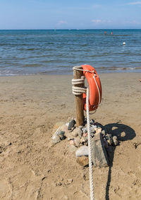 Coin-operated binoculars on wooden post at beach against sky