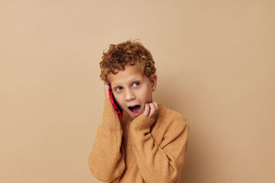 Boy looking away against beige background