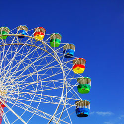 Low angle view of ferris wheel against blue sky