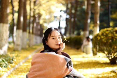 Portrait of woman against trees during sunny day