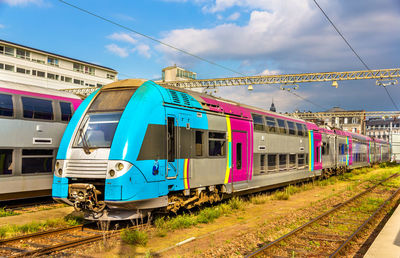 Train on railroad tracks in city against sky