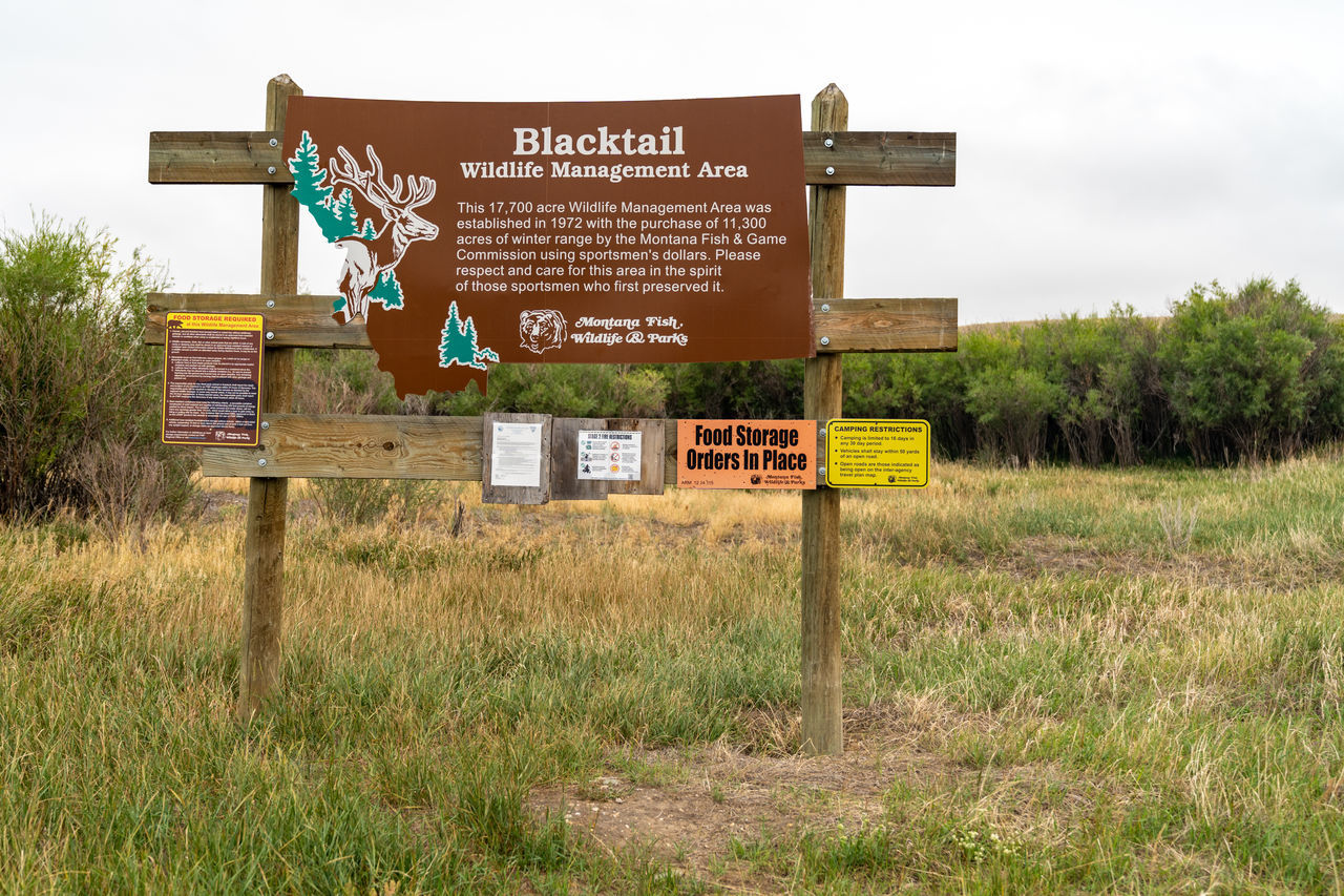 WARNING SIGN ON FIELD AGAINST SKY