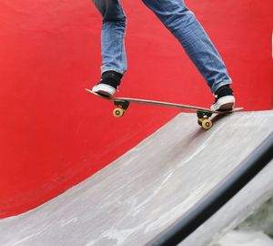 Low section of man skateboarding on red skateboard