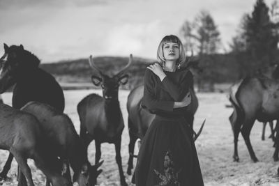 Young woman standing with animals on snow