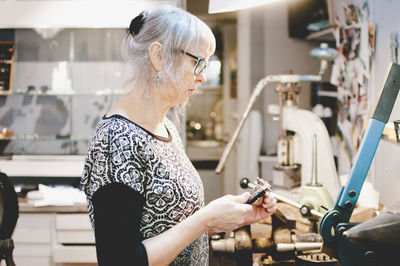 Side view of senior woman using caliper in jewelry workshop