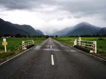 Empty road along landscape and mountains against sky