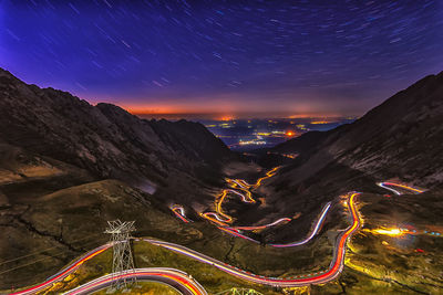 High angle view of light trails on mountain road against star trail