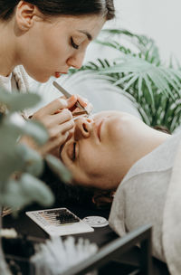 Portrait of a girl cosmetologist extending eyelashes to a woman.