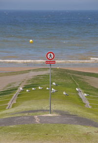 Information sign on shore by sea against sky
