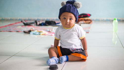 Portrait of cute boy sitting on tiled floor