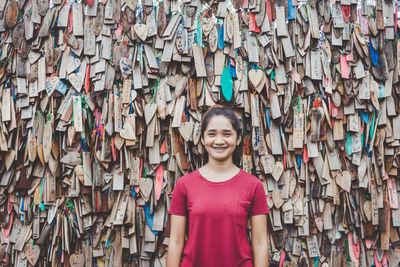 Portrait of woman standing against various wooden prayer blocks