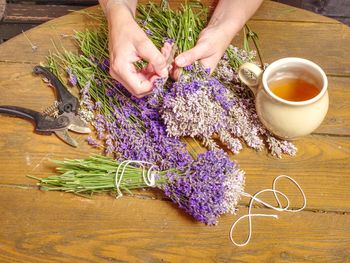 Aroma designer workplace. girl prepare lavander stalks for drying. wooden table with cup of  tea