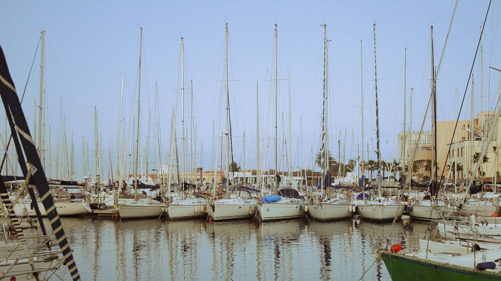 BOATS MOORED IN SEA AGAINST CLEAR SKY