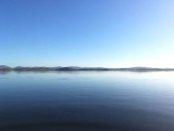 Scenic view of lake against clear blue sky