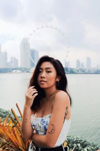 Portrait of beautiful woman standing in city against sky
