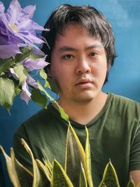 Close-up portrait of a serious young man against blue background 