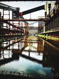 Bridge over river by buildings against sky