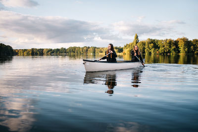 Men in boat on lake against sky