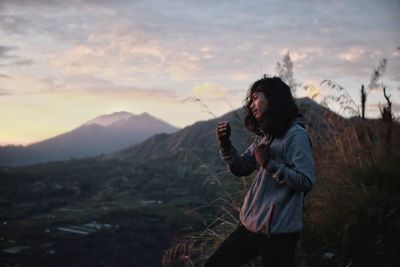 Woman standing on mountain against sky during sunset