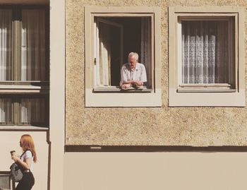 Man and woman standing by window of building