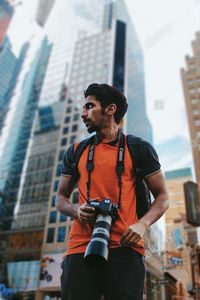 Young man looking away while standing in city