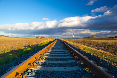 Surface level of railroad tracks on field against sky