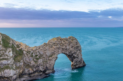 Rock formation in sea against sky