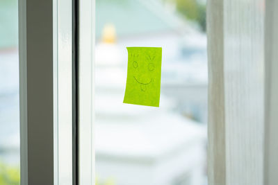 Close-up of anthropomorphic face drawn over adhesive note on glass window