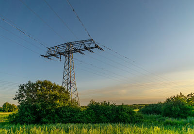 Low angle view of electricity pylon on field against sky