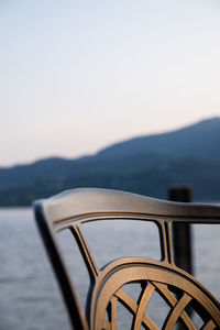 Close-up of wheel by lake against clear sky