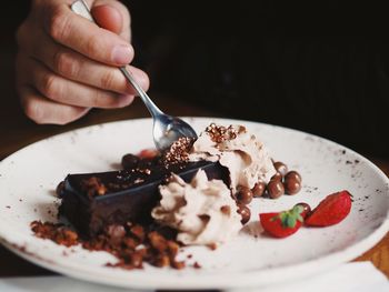 Close-up of hand holding ice cream in plate