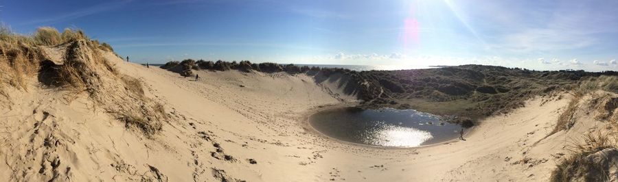 Panoramic view of sandy beach against sky on sunny day