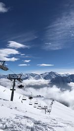 Ski lifts over snowcapped landscape against sky