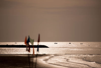 Silhouette people in sea against sky during sunset