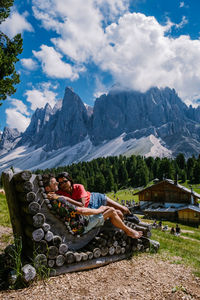 Man sitting on mountain against sky