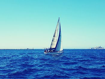 Sailboat sailing in sea against clear sky