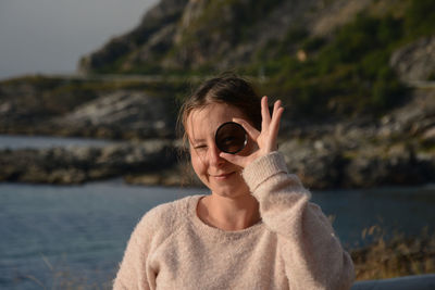 Portrait of woman looking through glass at beach