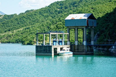 Built structure by lake in forest against sky