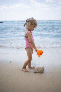 Cute toddler girl playing with water on the beach. vacation on the sea shore concept. summertime fun